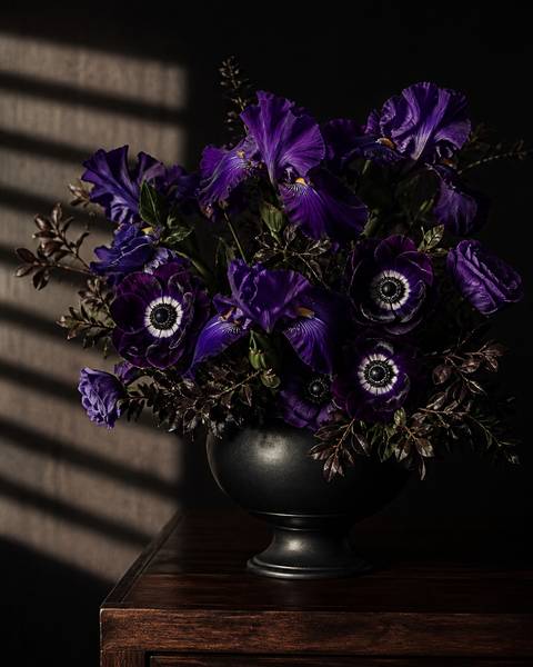 Dramatic dark purple iris and deep purple anemones in a black ceramic urn